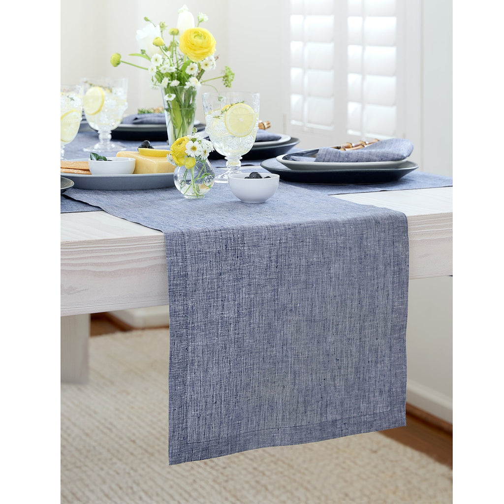 Dining table set with a blue runner, plates, and yellow flowers.