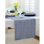 Dining table set with a blue runner, plates, and yellow flowers.