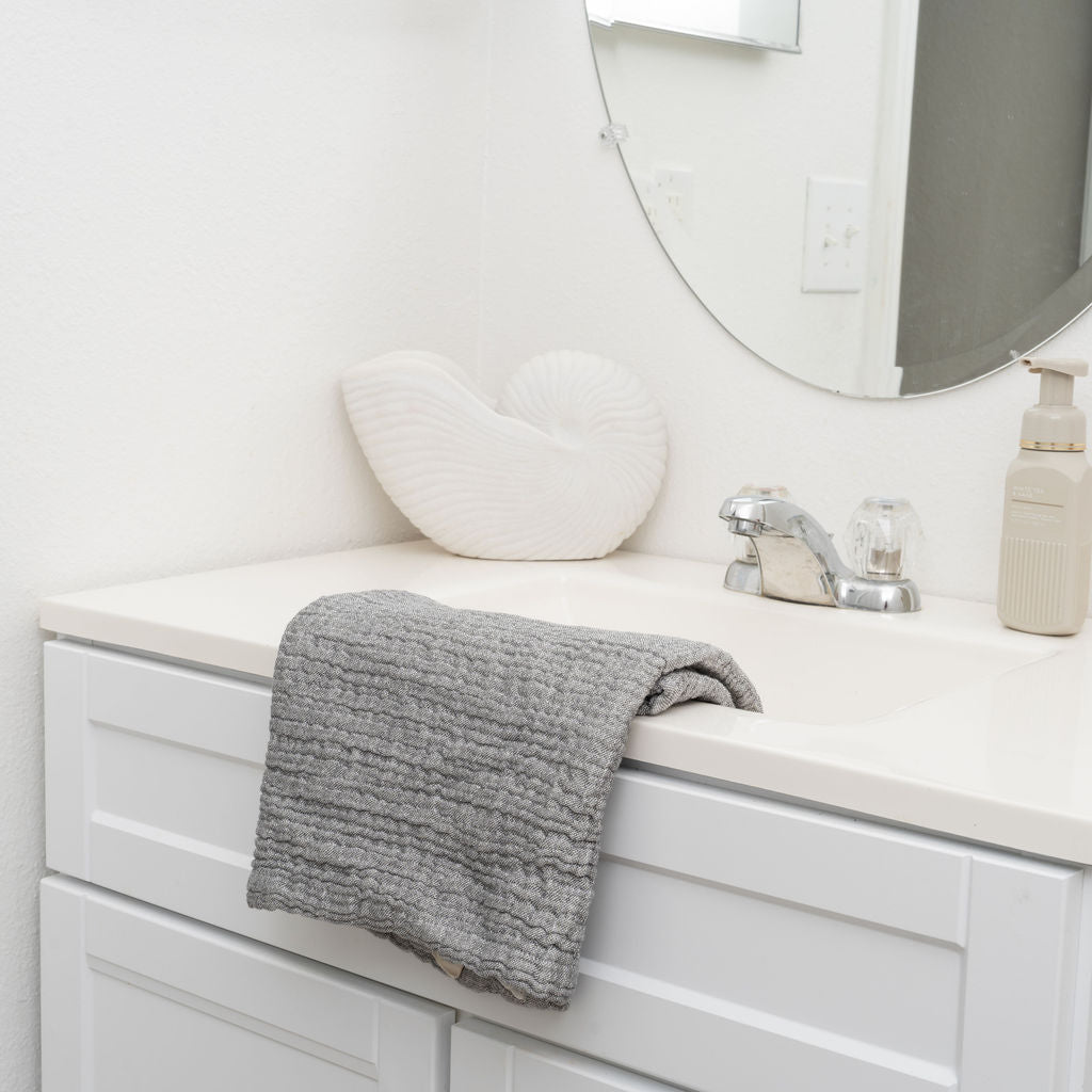 Bathroom vanity with a gray towel draped over the edge, a sink, and a mirror.