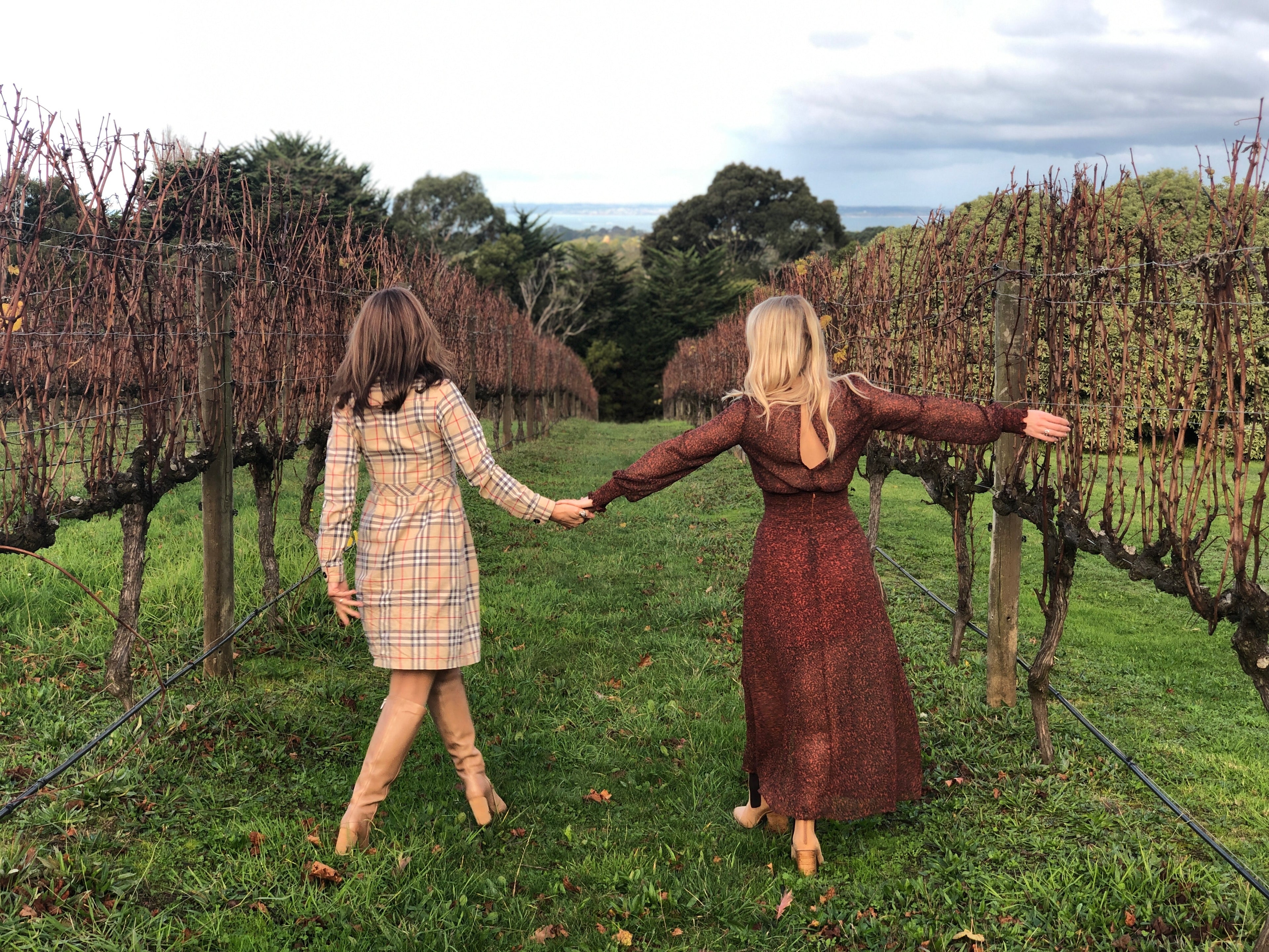 2 women walking in vineyard wearing vintage clothing